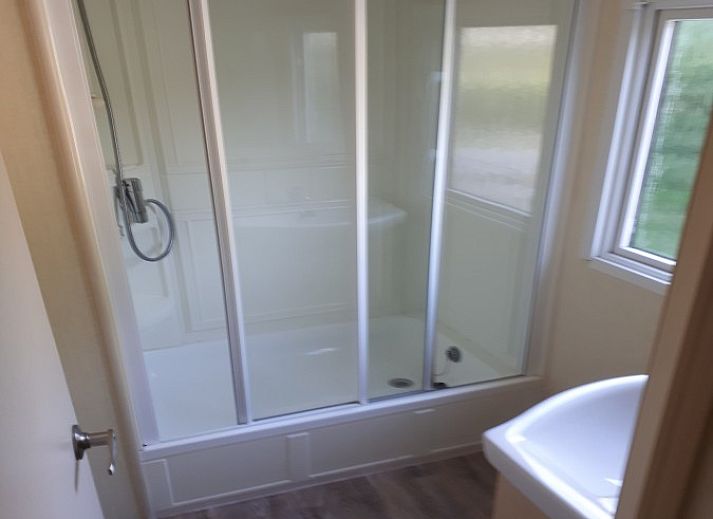 Relax in the quiet sandy garden of Chalet Sunrise in Ouddorp, Zeeland, with comfortable chairs and surrounding nature.