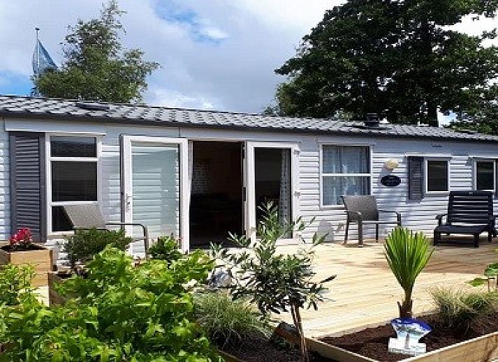 Enjoy the green surroundings and wooden veranda at Chalet Sunrise with private beach garden in Ouddorp, Zeeland.