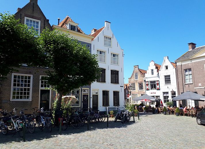 Spacious wooden veranda with modern seating at Chalet Sunrise in Ouddorp, Zeeland, surrounded by a green garden.