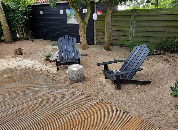 Spacious wooden veranda with modern seating at Chalet Sunrise in Ouddorp, Zeeland, surrounded by a green garden.