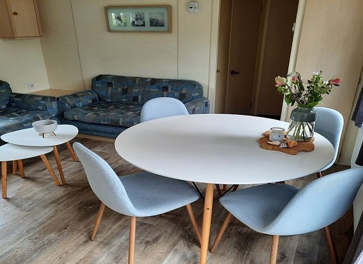 Spacious wooden veranda with modern seating at Chalet Sunrise in Ouddorp, Zeeland, surrounded by a green garden.