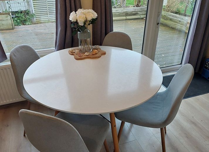 Spacious wooden veranda with modern seating at Chalet Sunrise in Ouddorp, Zeeland, surrounded by a green garden.