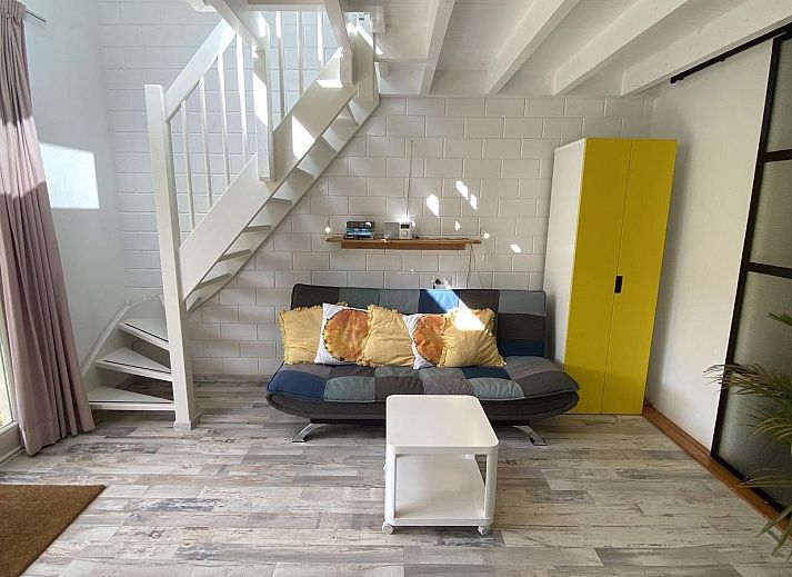 Sonnige Terrasse am Ferienhaus VZ991 in Ouddorp, Suedholland, mit bequemen Stuehlen und gruener Umgebung.