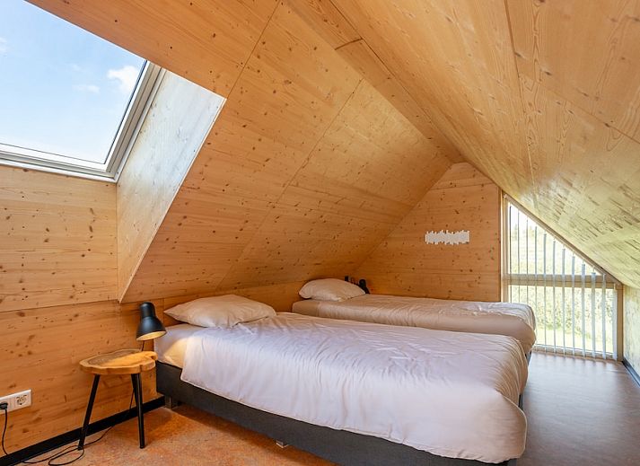 Gezellige binnenruimte van ECO Cottage in Ouddorp, Zuid-Holland, met houten interieur en comfortabele zitbank, ideaal voor ontspanning.