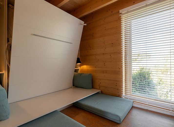 Gezellige binnenruimte van ECO Cottage in Ouddorp, Zuid-Holland, met houten interieur en comfortabele zitbank, ideaal voor ontspanning.