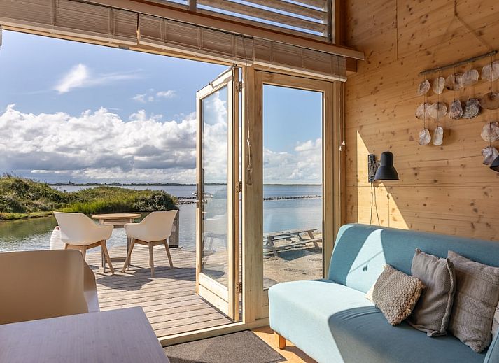 Gezellige binnenruimte van ECO Cottage in Ouddorp, Zuid-Holland, met houten interieur en comfortabele zitbank, ideaal voor ontspanning.