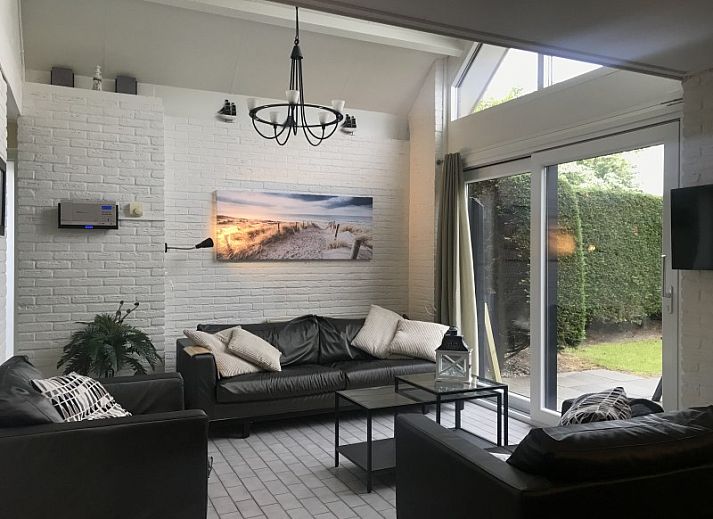 Eetkamer van Vakantiehuis Ouddorp met stijlvolle houten tafel en kunst aan de muur in Ouddorp.