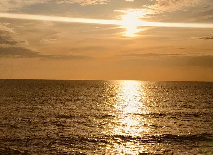 Eetkamer van Vakantiehuis Ouddorp met stijlvolle houten tafel en kunst aan de muur in Ouddorp.