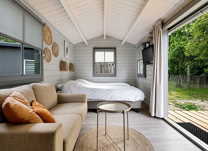 Innenbereich des Kampeerchalet de Zeekoet in Ouddorp mit gemuetlicher Sitzecke und Blick auf die Natur von Goeree-Overflakkee.