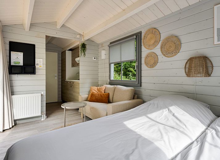 Innenbereich des Kampeerchalet de Zeekoet in Ouddorp mit gemuetlicher Sitzecke und Blick auf die Natur von Goeree-Overflakkee.