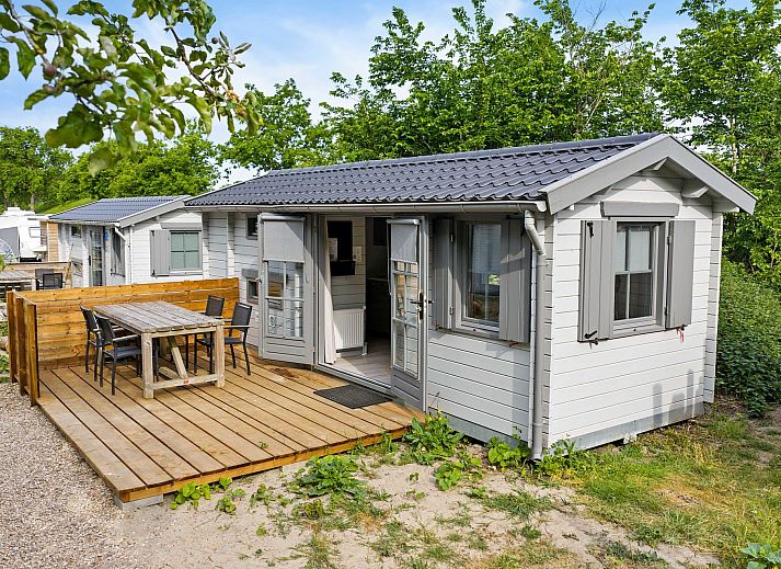 Terrasse des Kampeerchalet de Zeekoet in Ouddorp mit Esstisch und Stuehlen aus Holz, umgeben von der Natur von Goeree-Overflakkee.