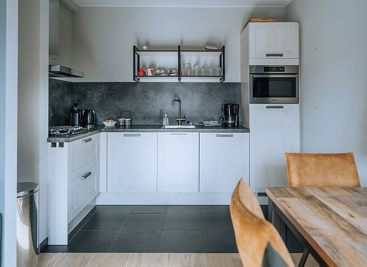 Dining room in ZH416 vacation home, Ouddorp, Goeree-Overflakkee, with modern furnishings and atmospheric lighting.