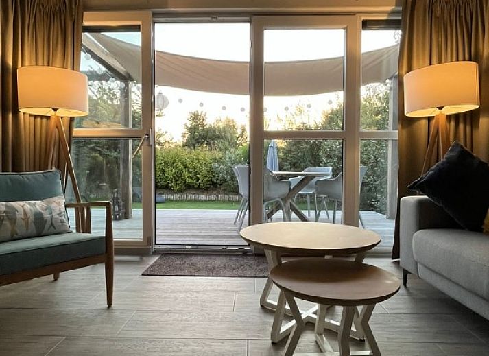 Uitzicht vanuit de woonkamer van DichterbijZee in Ouddorp op de groene tuin en het terras, ideaal voor natuurliefhebbers.