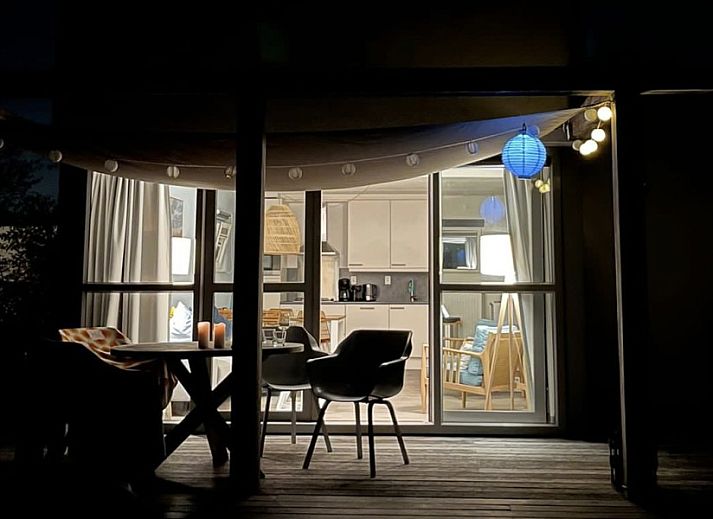 Uitzicht vanuit de woonkamer van DichterbijZee in Ouddorp op de groene tuin en het terras, ideaal voor natuurliefhebbers.