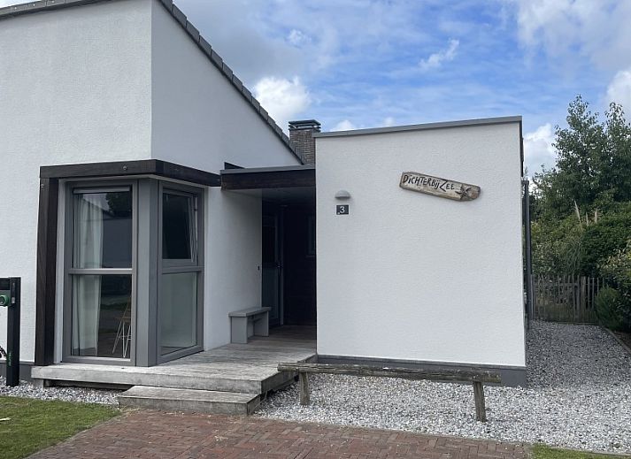 Uitzicht vanuit de woonkamer van DichterbijZee in Ouddorp op de groene tuin en het terras, ideaal voor natuurliefhebbers.