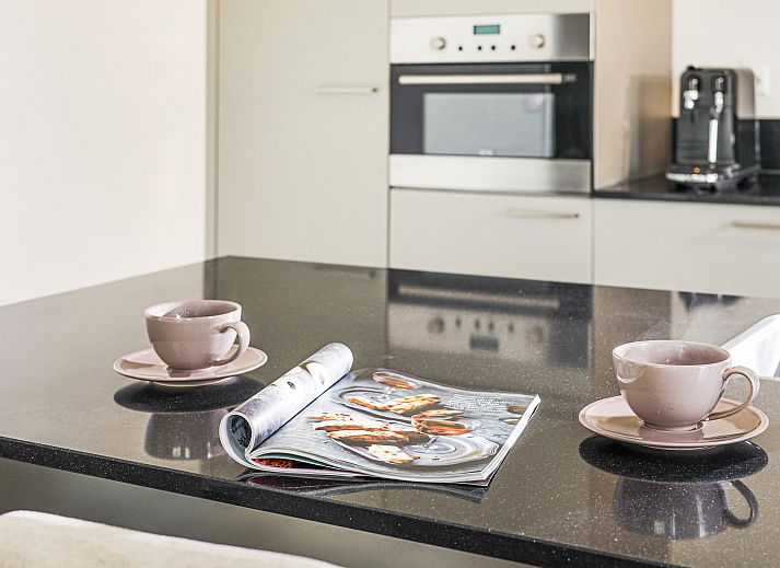 Moderne Kueche in der 6-Personen-Villa Zeeduin des Strand Resort Ouddorp Duin in Ouddorp, Suedholland, mit Kochinsel und Zugang zur Terrasse.