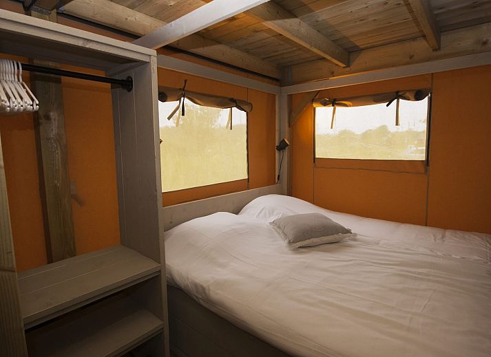 Veranda des Safarizeltes Duinroos in Ouddorp, einer Glamping Lodge in Goeree-Overflakkee, Suedholland, umgeben von gruener Natur.