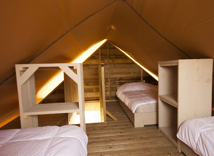 Veranda des Safarizeltes Duinroos in Ouddorp, einer Glamping Lodge in Goeree-Overflakkee, Suedholland, umgeben von gruener Natur.