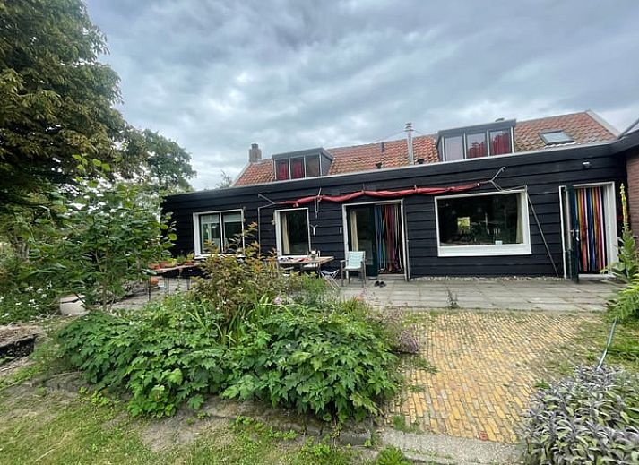 Ruime woonkamer in Vakantiehuisje in Goedereede, met houten balken en comfortabele zitplaatsen.
