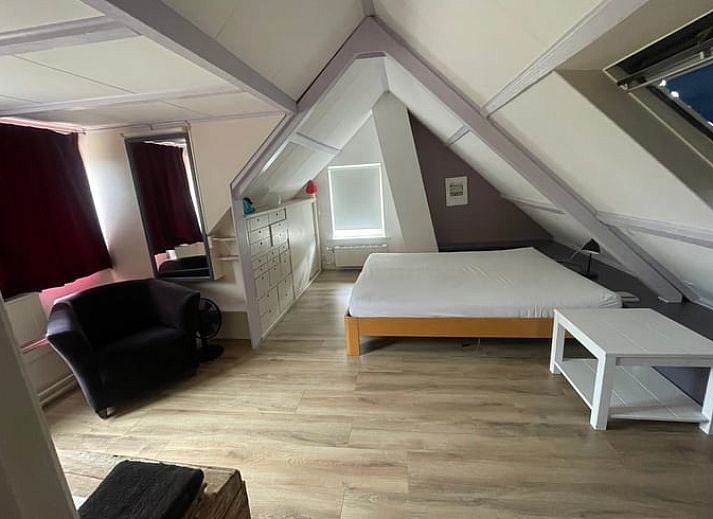 Ruime woonkamer in Vakantiehuisje in Goedereede, met houten balken en comfortabele zitplaatsen.