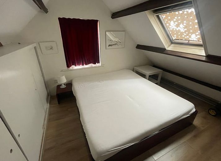 Ruime woonkamer in Vakantiehuisje in Goedereede, met houten balken en comfortabele zitplaatsen.