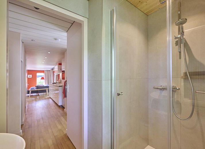 Veranda von Huisje Joep in Goedereede, schoene Terrasse mit roten Stuehlen, umgeben von Natur.