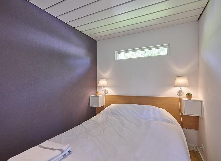 Veranda von Huisje Joep in Goedereede, schoene Terrasse mit roten Stuehlen, umgeben von Natur.