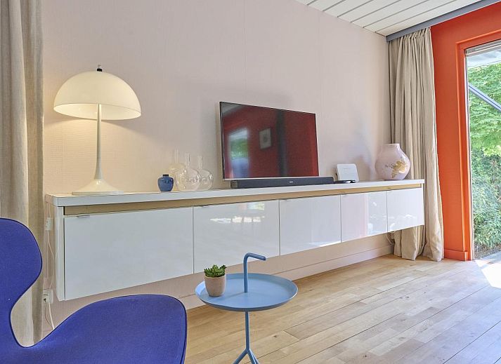 Veranda von Huisje Joep in Goedereede, schoene Terrasse mit roten Stuehlen, umgeben von Natur.