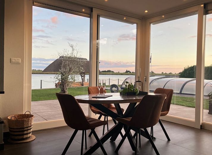 Wijnglazen op houten tafel aan het water bij Vakantiehuis in Ammerstol, perfect voor een avondje uit.