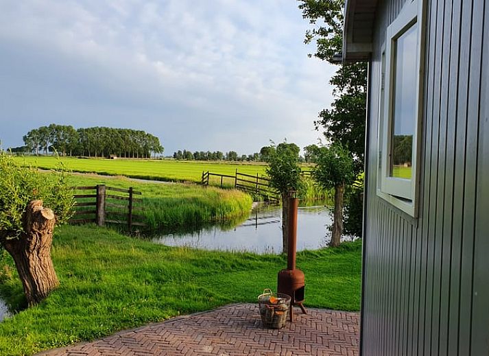 Terrasse von Huisje in Haastrecht, Ferienunterkunft in Haastrecht, Suedholland, mit Liegestuehlen und gruener Umgebung.