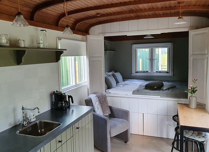 Terrasse von Huisje in Haastrecht, Ferienunterkunft in Haastrecht, Suedholland, mit Liegestuehlen und gruener Umgebung.