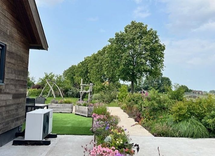 Cottage in Noorden, Green Heart, South Holland with wooden facade and colorful flower boxes, surrounded by lush nature.