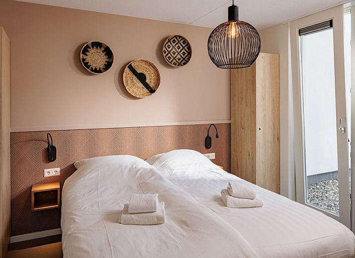 Stilvolles Wohnzimmer im Bungalow 8, Noordwijkerhout, Nordseekueste, mit gemuetlicher Sitzecke und Blick auf die Terrasse.