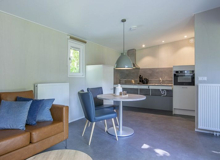 Gezellige woonkamer in Comfort 2 Mindervalide chalet, Kijkduin, met comfortabele zithoek en decoratie.