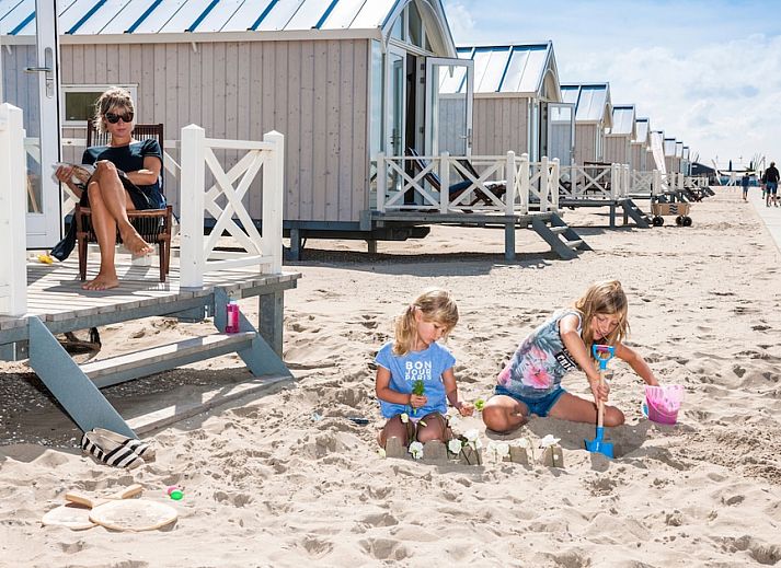 Haagse Strandhuisjes 5 in Kijkduin, Zuid-Holland, vakantiehuis aan de Noordzeekust met veranda en uitzicht op de duinen bij zonsondergang.