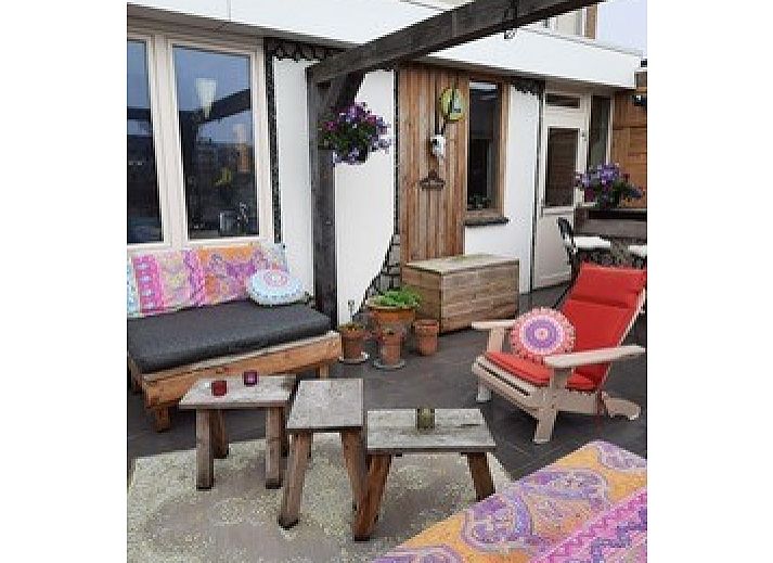 Entspannte Terrasse im Ferienhaus am Meer in Katwijk aan Zee, Nordseekueste, Suedholland, mit bunten Sitzgelegenheiten und Pflanzen.