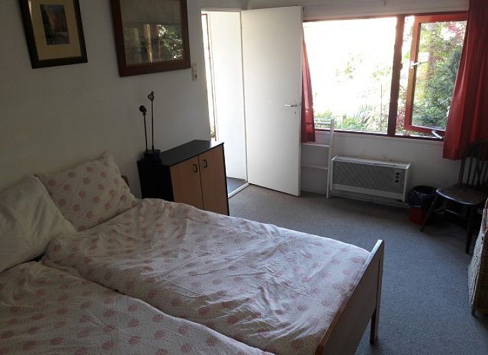 Zonnig terras bij Om de Loop vakantiehuis in Rockanje, Zuid-Holland, omgeven door groen.