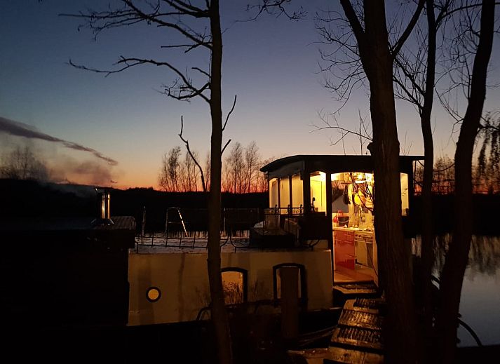 Enjoy the unique houseboat experience at ZH491, a vacation home in Rotterdam, South Holland, with a beautiful terrace and green surroundings.