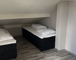 Gezellige slaapkamer in TXL Huisje 299, een vakantiehuis in De Cocksdorp op Texel, Waddeneilanden, met comfortabele bedden onder een schuin dak.