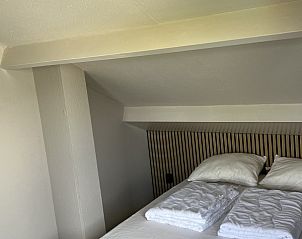 Sfeervolle slaapkamer in TXL Huisje 299, een vakantiehuis in De Cocksdorp, Texel, met een comfortabel bed en rustieke houten accenten.