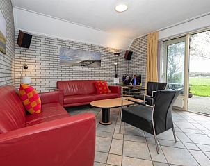 Gezellige woonkamer in Vakantiehuis Schelpenoord 129, De Cocksdorp, Texel, met comfortabele zitruimte en uitzicht op groene omgeving.