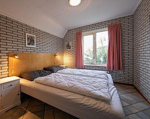 Rustgevende slaapkamer in Vakantiehuis Schelpenoord 129, De Cocksdorp, Texel, met comfortabel tweepersoonsbed en natuurlijke lichtinval.