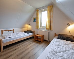 Gezellige kindvriendelijke slaapkamer in Vakantiehuis Schelpenoord 129, De Cocksdorp, Texel, met twee eenpersoonsbedden en wiegje.