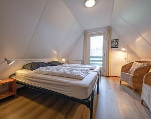 Knusse zolderkamer met tweepersoonsbed in Vakantiehuis Schelpenoord 129, De Cocksdorp, Texel, met toegang tot balkon en veel licht.