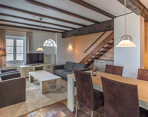 Gezellige woonkamer in Type T-3 vakantiehuis, Texel met houten balken en ruime zithoek.