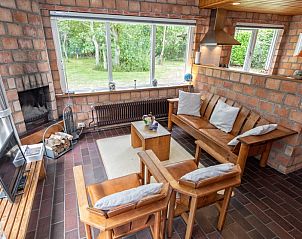 Comfortabele zithoek in Bungalow Tamarisk 138, Texel, met open haard en tuinzicht.