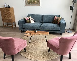 Gezellige zitruimte in Zeerus, De Cocksdorp, Texel met blauwe bank en roze stoelen.