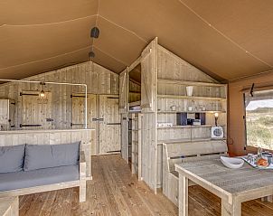 Eethoek in Sluftervallei safaritent, De Cocksdorp, Texel, Waddeneilanden, met houten tafel en banken.