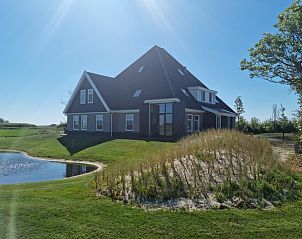 Vacation home De Slufter in De Cocksdorp, Texel offers a beautiful view of nature with a serene pond and green surroundings.