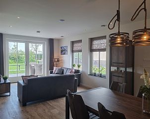 The cozy living room of Holiday home De Slufter in De Cocksdorp, Texel offers a comfortable space overlooking the garden.